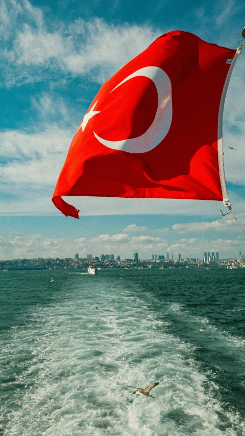 a red flag on the water with buildings in the background