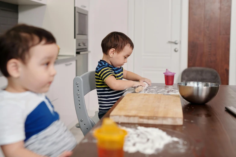 two small boys are playing with the table in the kitchen