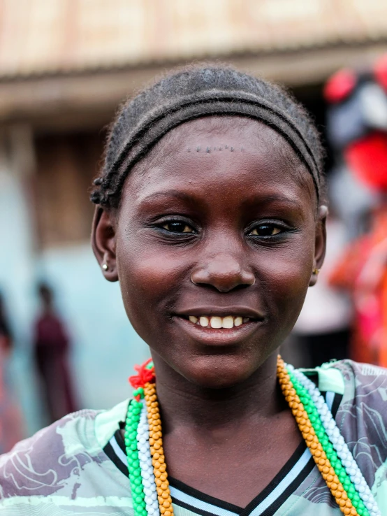 the smiling woman wearing two necklaces is posing for the camera