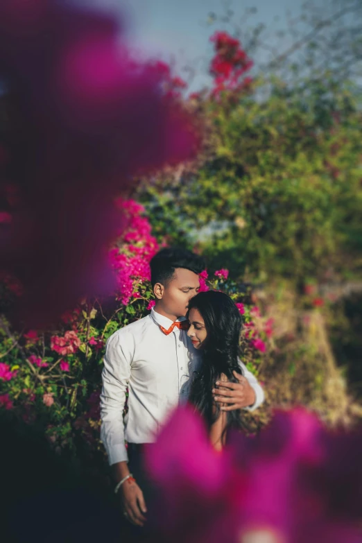 an asian couple hugging and emcing in front of beautiful pink flowers