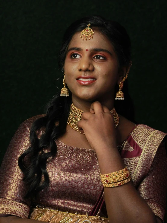 a close up of a woman wearing a gold dress and jewelry