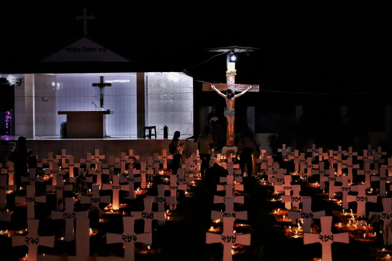 a group of people standing next to a church on a field with crosses