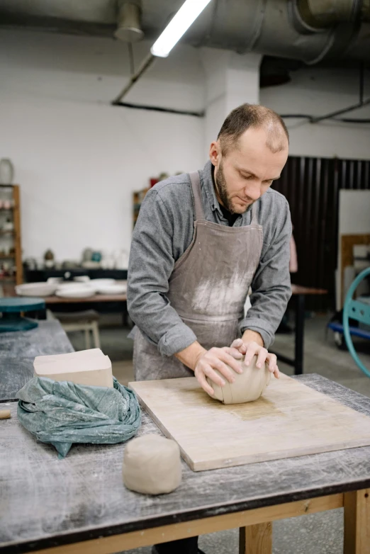 a man using a pottery wheel in a small room