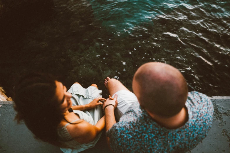 a man and woman are laying down by the water