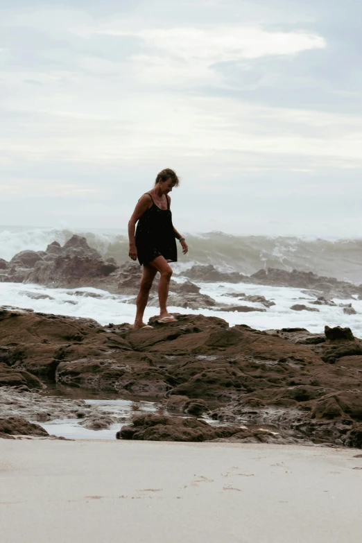 an athletic woman stands on some rocks next to the ocean