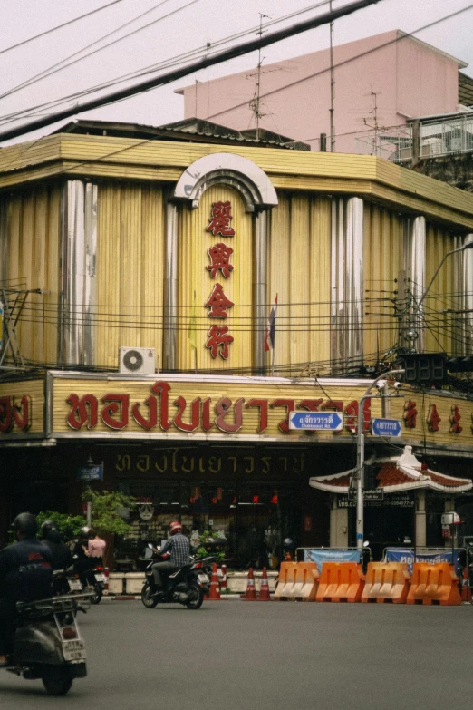 a man on a motorcycle going down the street in front of an asian restaurant