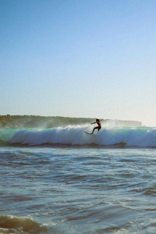 a surfer is riding an ocean wave in the distance