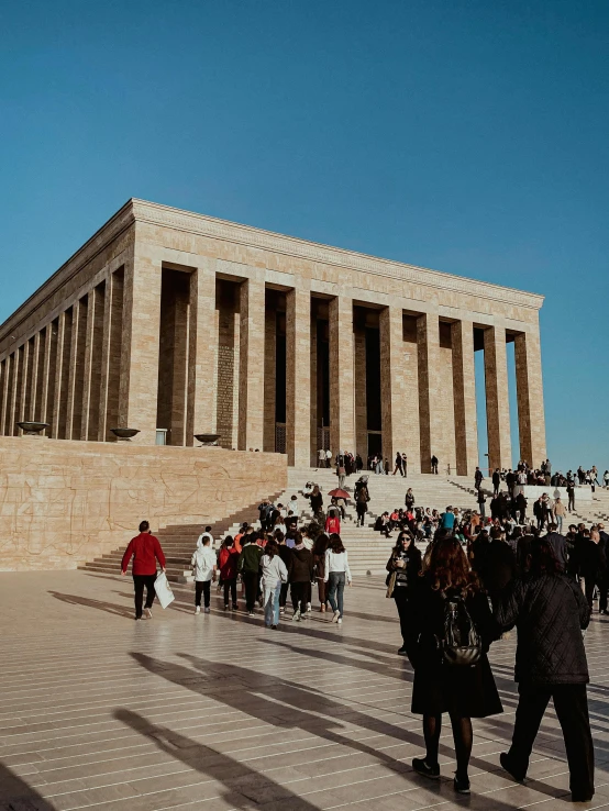 people walking around a small hill in front of a building