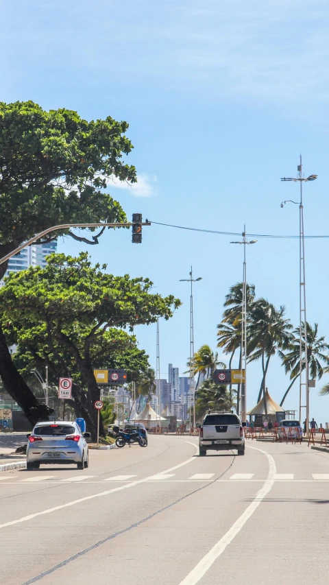 cars travelling down a street next to trees