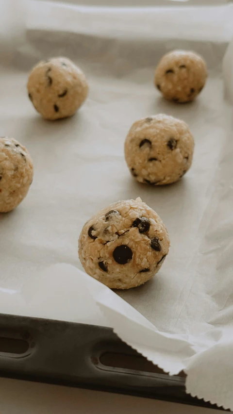 twelve cookies with chocolate chips sit on a piece of paper