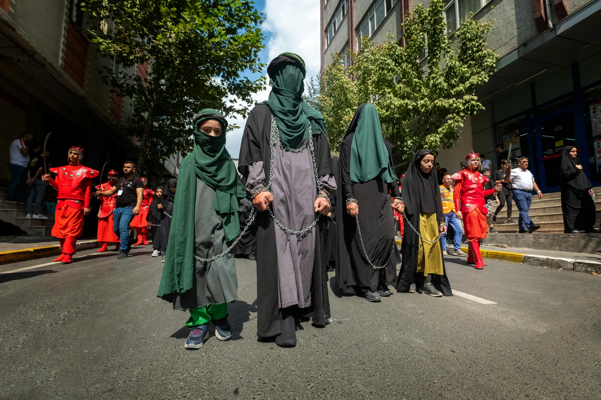 a group of men in dark colored clothes, with arms around one another, are walking on the street