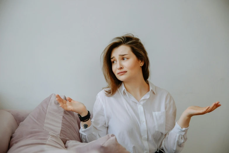 a woman in a white shirt sitting on a bed