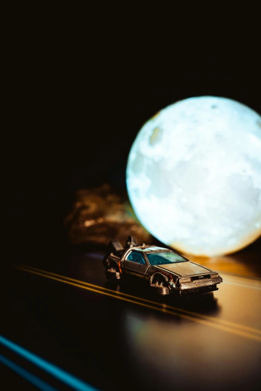 a toy car on a dark road under a full moon