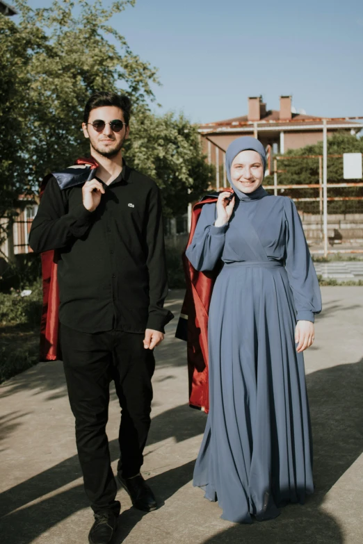 a man and woman stand in front of some clothing