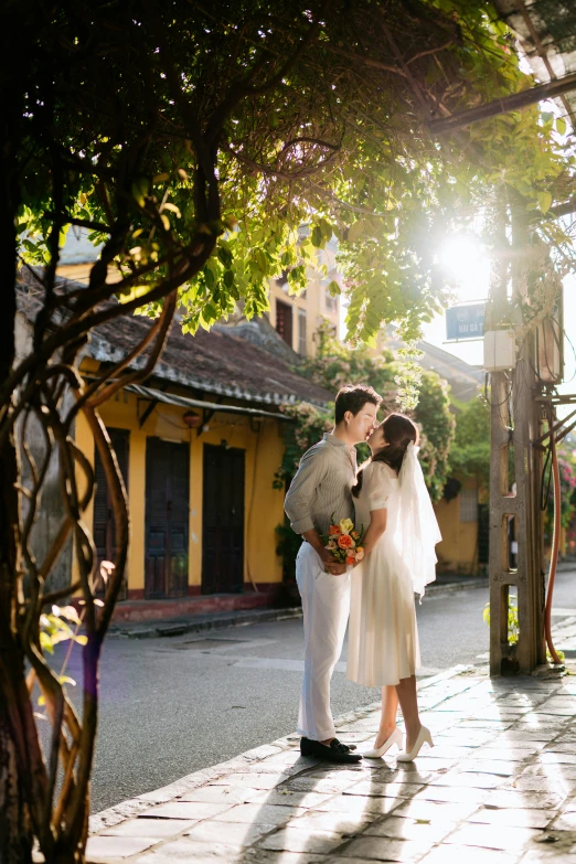 two brides in white are kissing near a pergolic arch