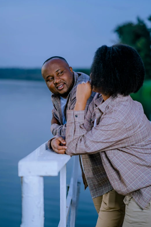 two women stand beside each other on a pier with a blue lake behind them