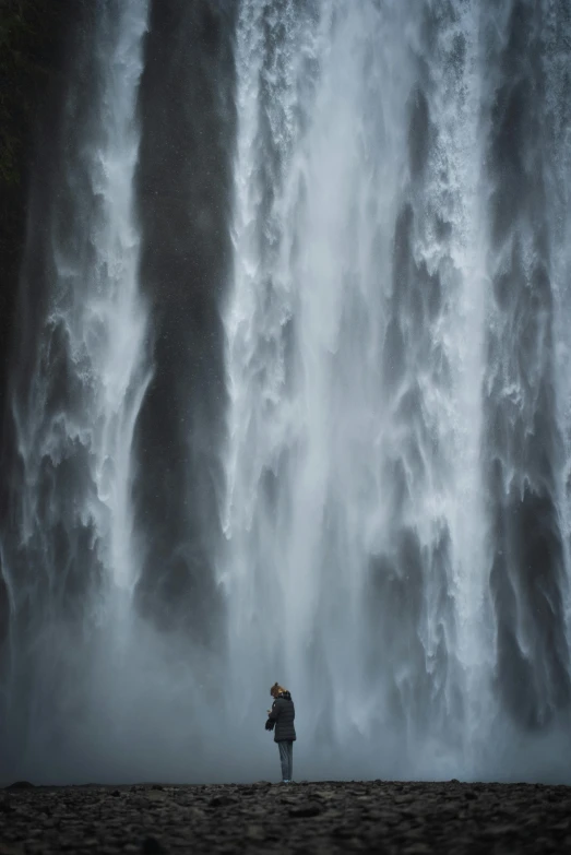 a person is standing beneath a giant waterfall