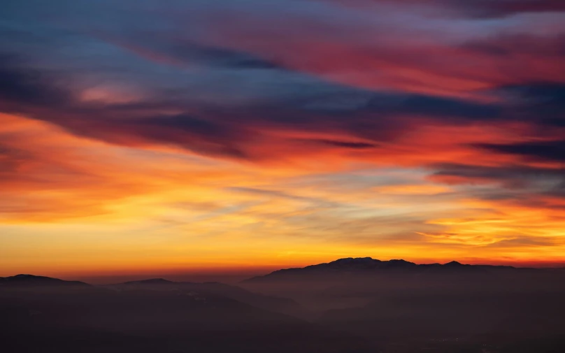 a plane flying over some mountains under a cloudy sky