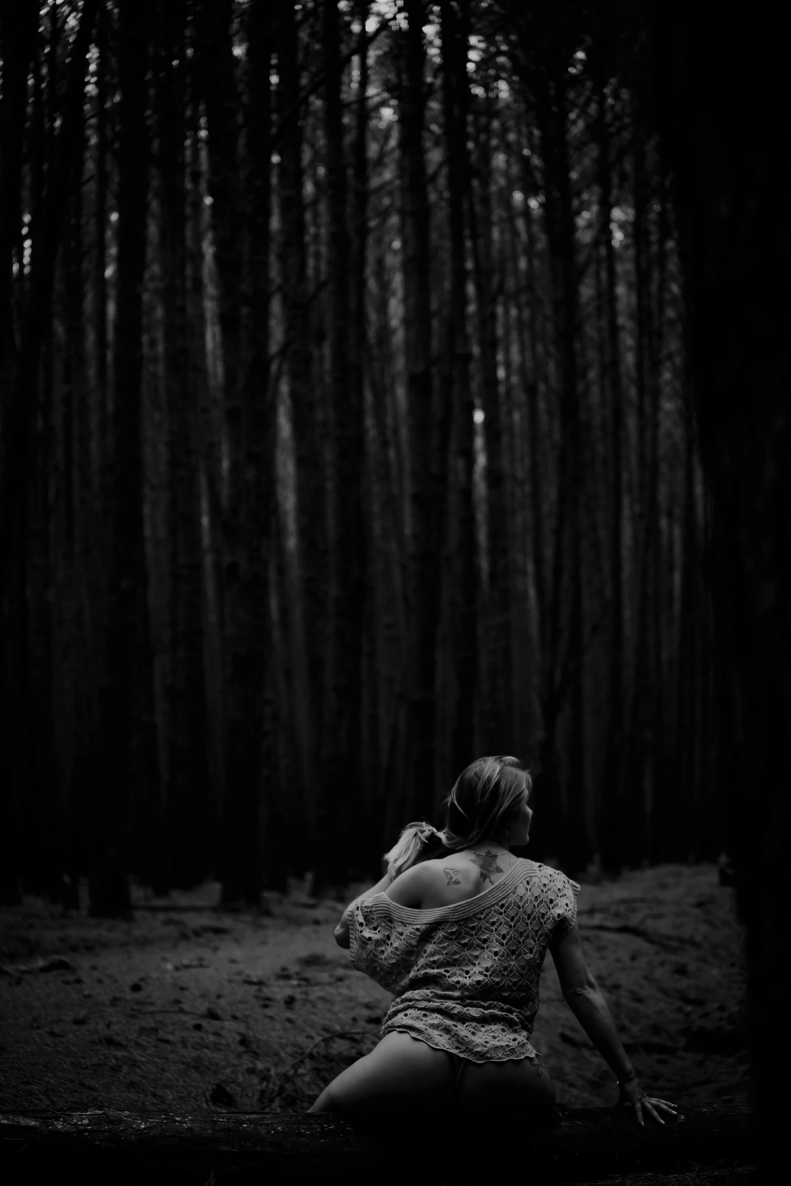 the woman is sitting on a bench in the woods