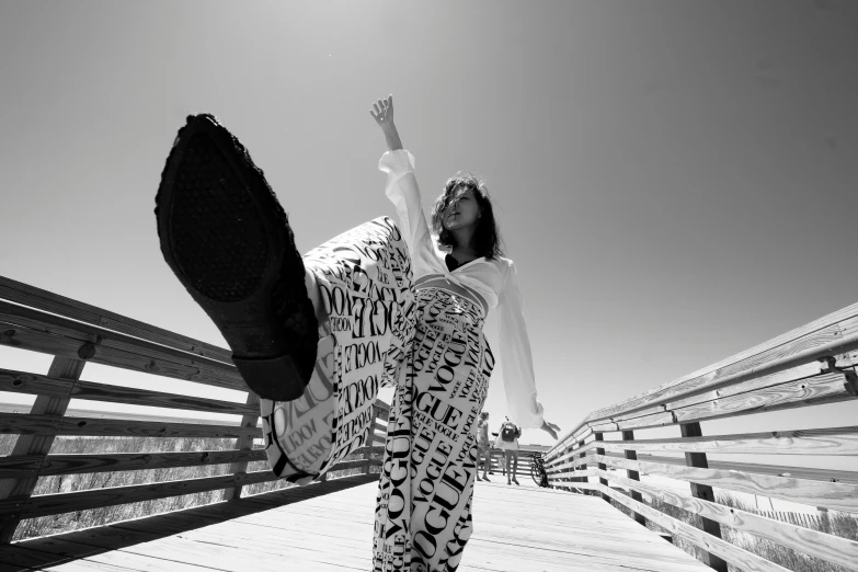 a person stands on a boardwalk holding their feet up