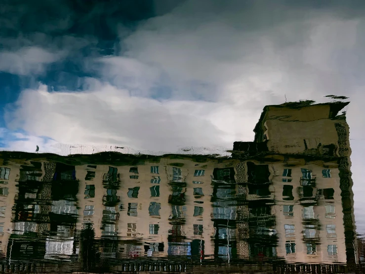 a building is reflecting a sky with clouds