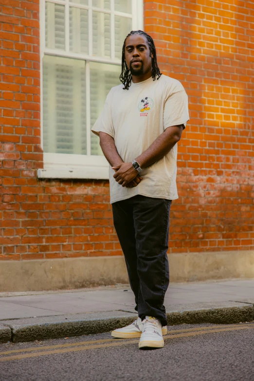 a man with long dreadlocks leaning against a brick building