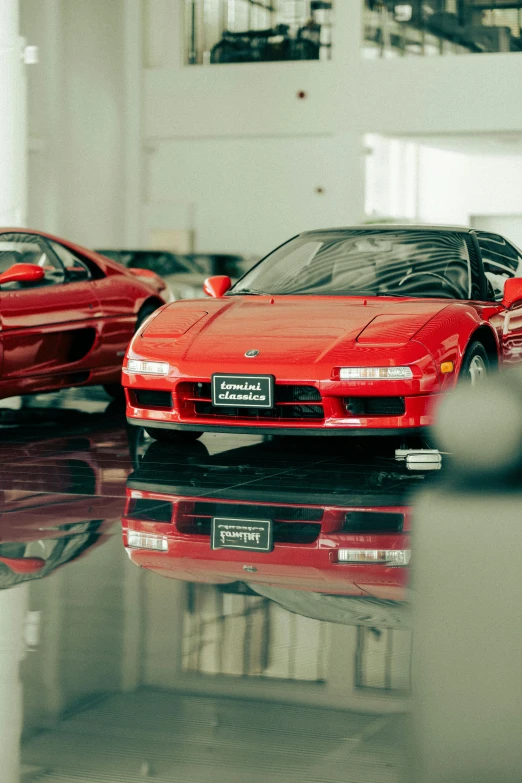 a row of sports cars in a building with their reflection on the floor