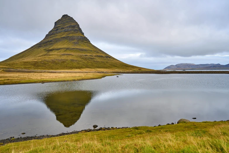 a mountain with some clouds in the sky and a reflection in the water