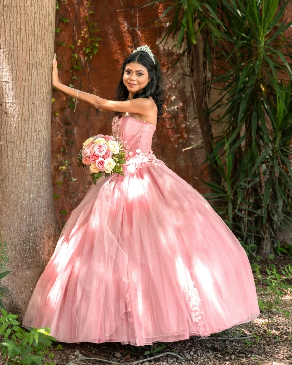 the woman in a pink dress has her hand out near the tree