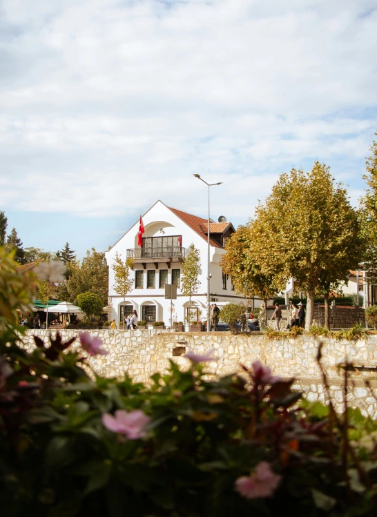 an old house with a white facade with lots of flowers in the front