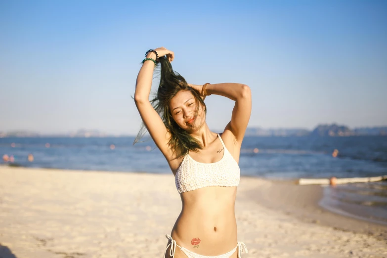 a young woman in white bikini and no panties standing on beach