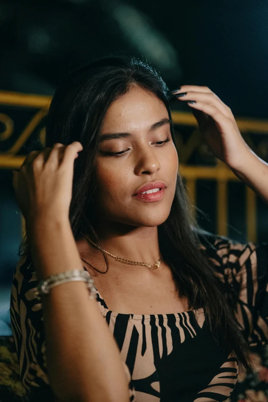 a woman sitting in front of a wall holding her hair