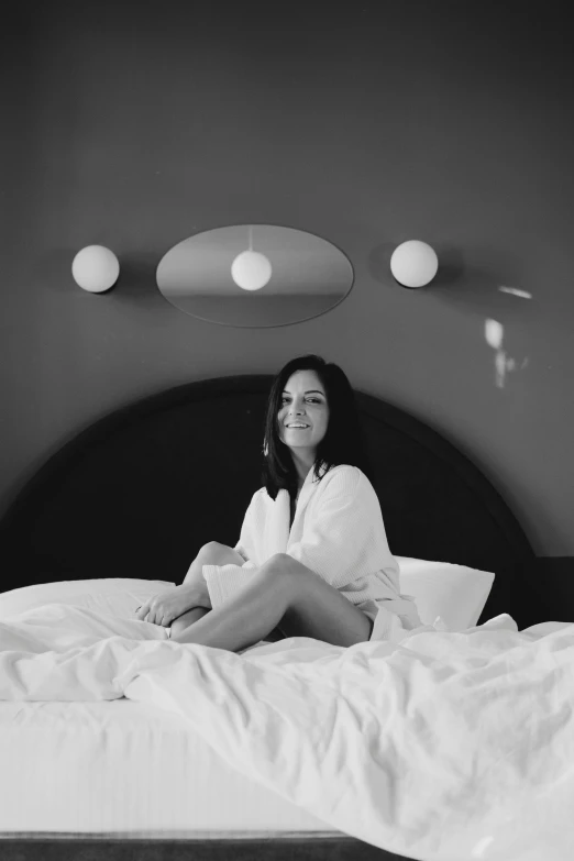 a woman sits on the edge of a bed