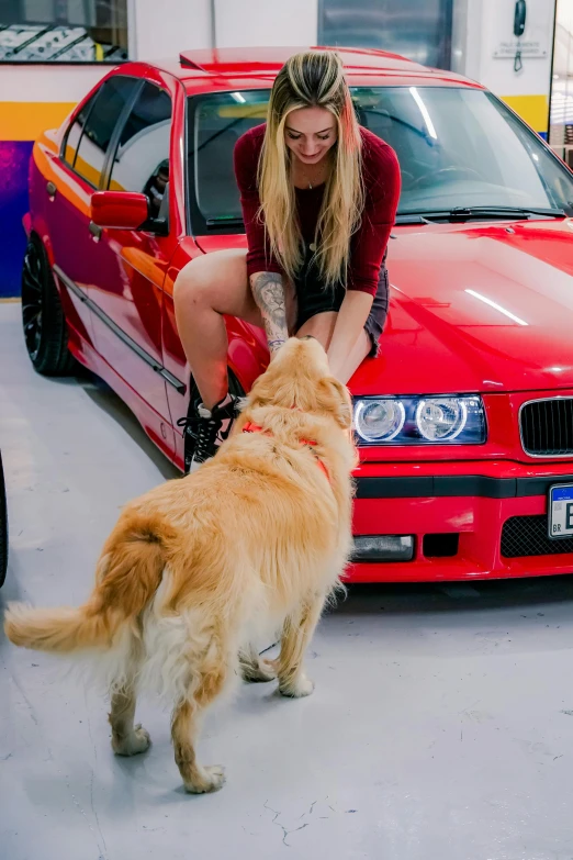 a woman pets a dog in front of her car