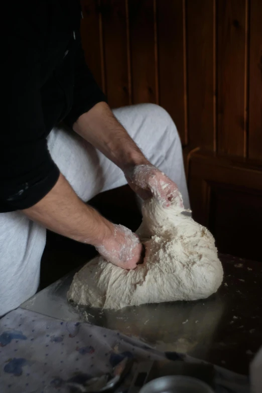 someone in black shirt kneading a fake sheep on metal counter