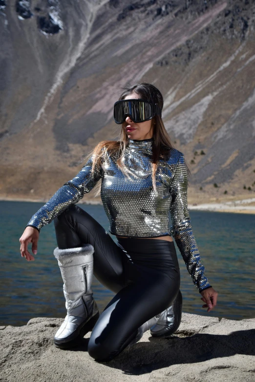 a woman in leather pants is sitting on a rock