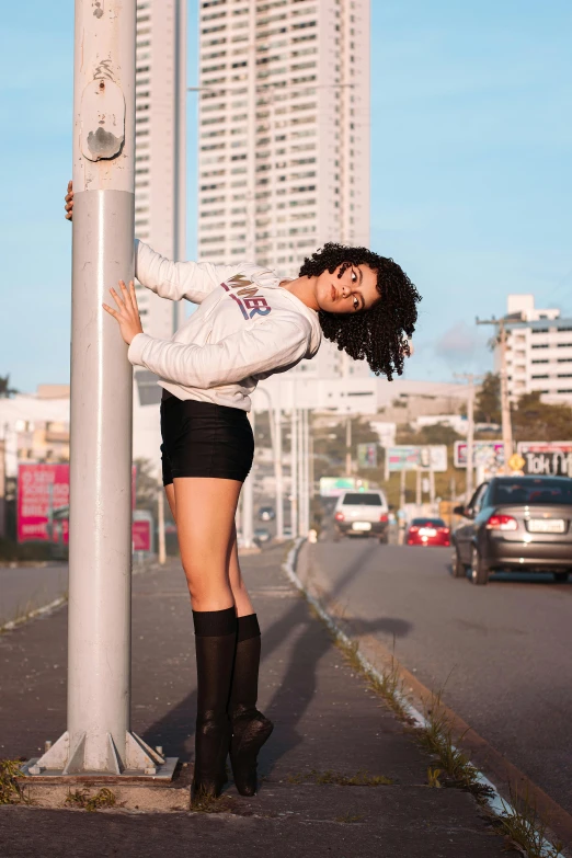 a girl standing on the side of a street pole