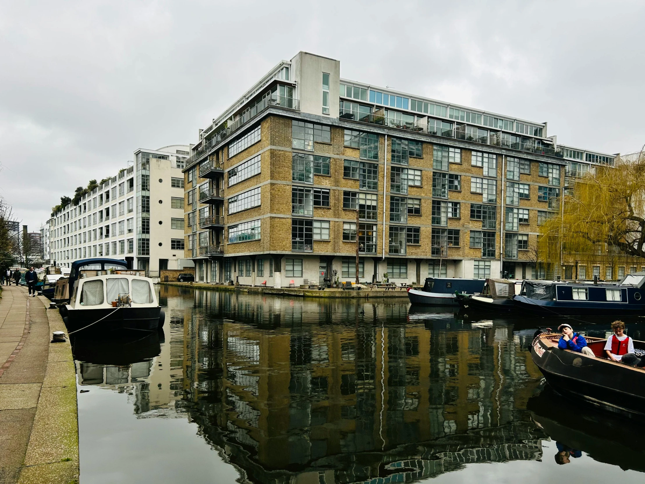 people are in boats floating on the water in front of a large apartment building