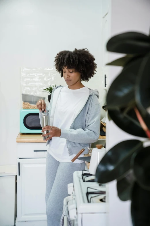 a woman wearing sweatpants holding a cup in her hand