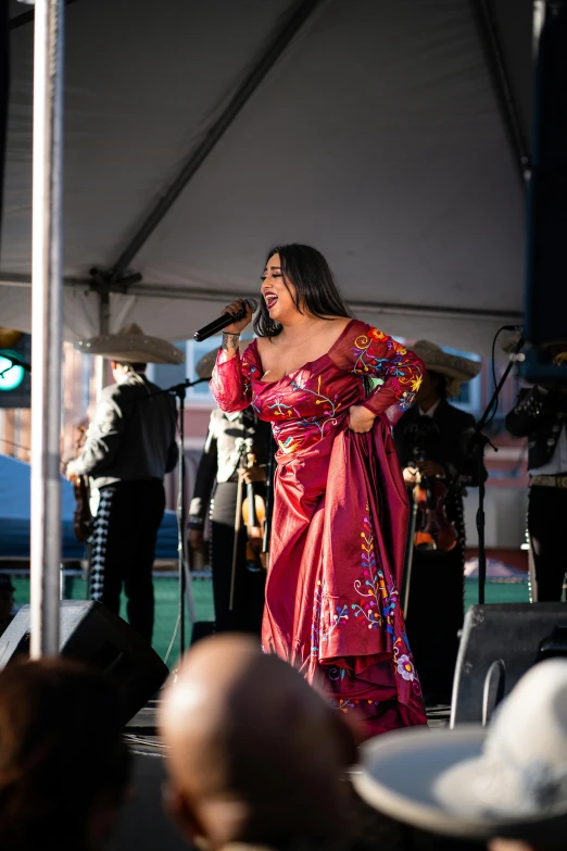 a woman wearing a pink dress while standing in front of microphone