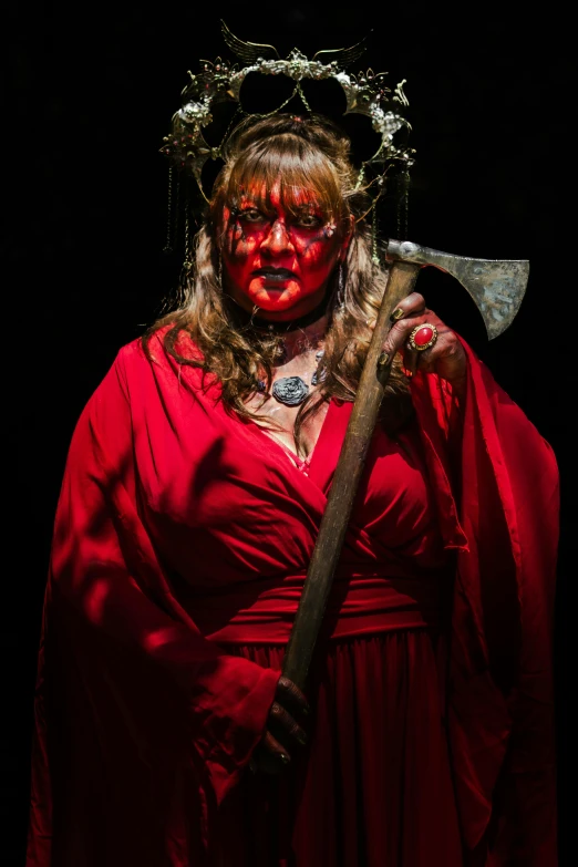 a woman in red is wearing a crown and holding a giant ax