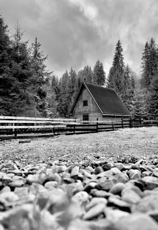 an old cottage on a gravel bank with rocks in the foreground