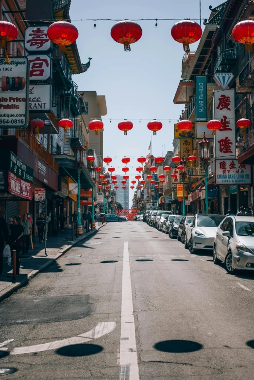 a group of red lanterns are hanging over an empty street