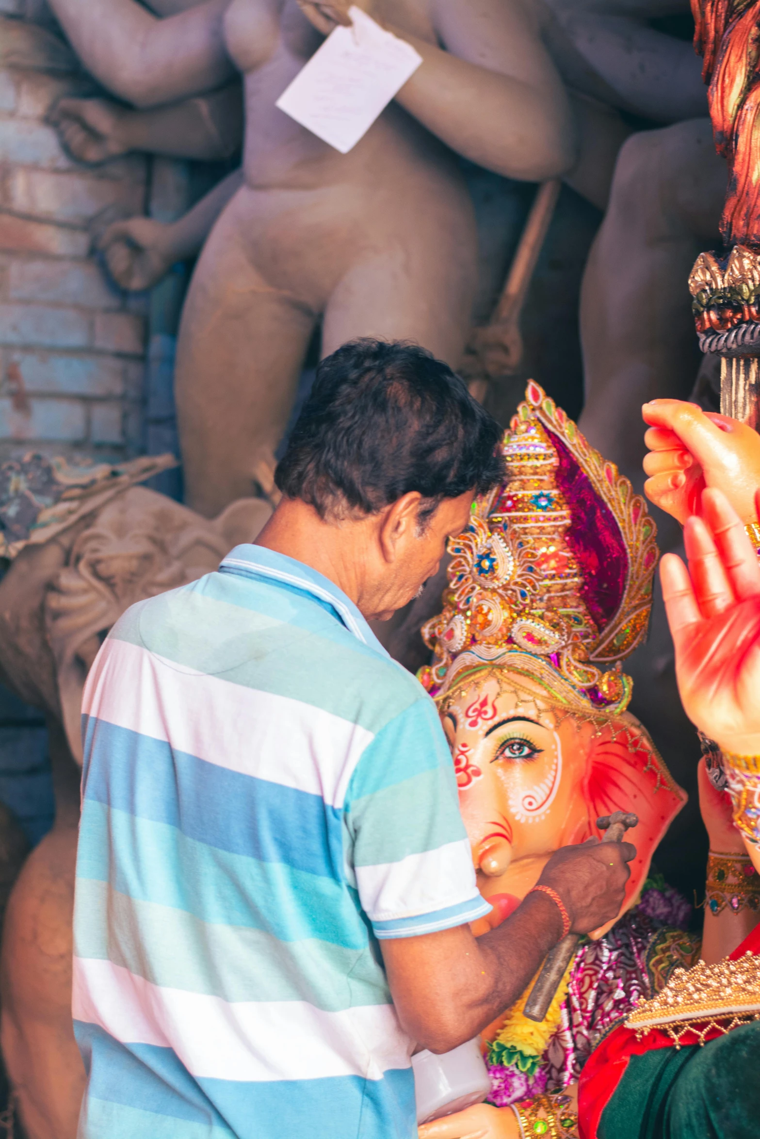 a man in a colorful cloth standing next to an elaborately decorated idol