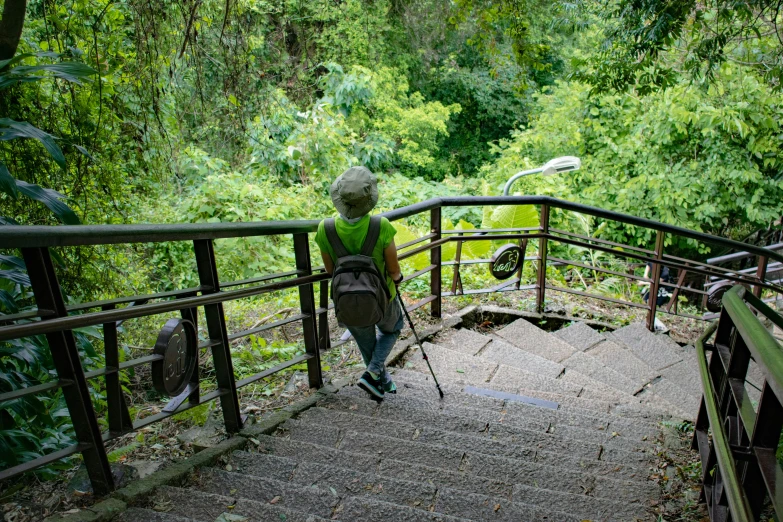 a little boy wearing a hat walking up some stairs