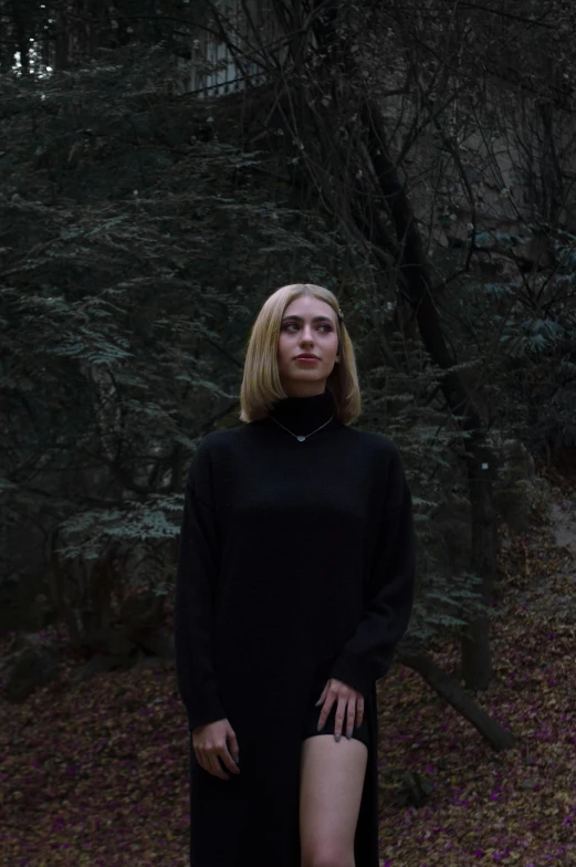 a blonde woman standing in the woods, posing