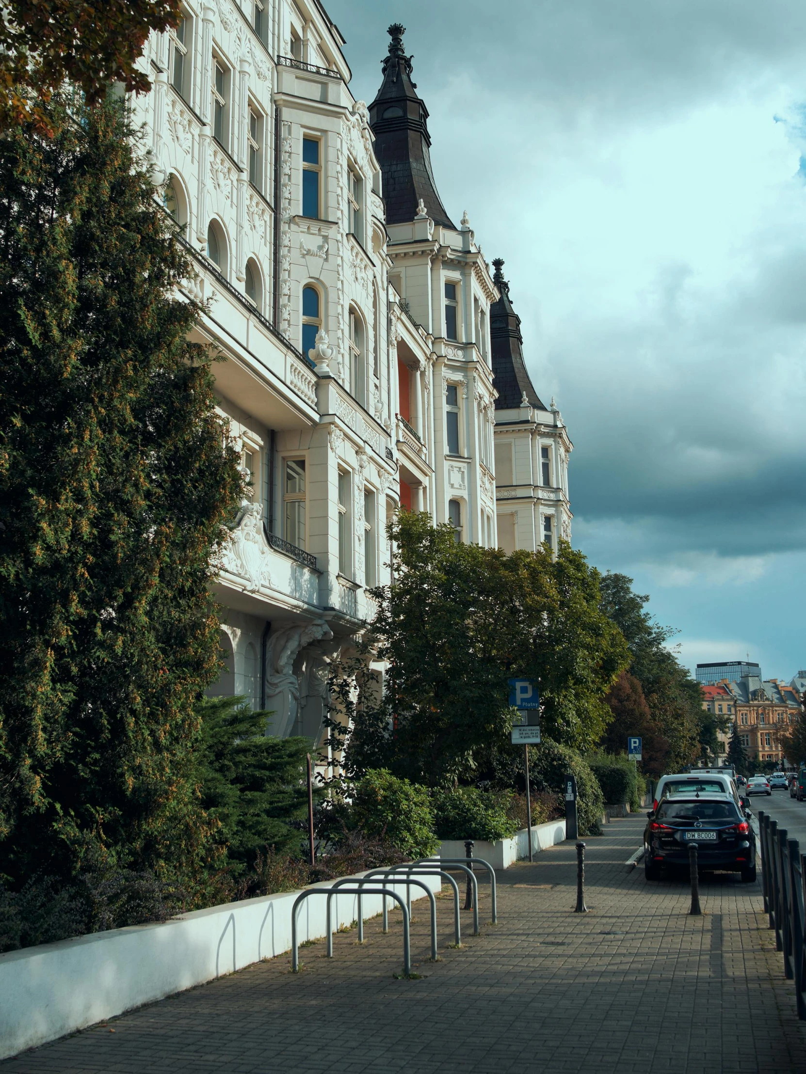 the buildings of a city street with parked cars