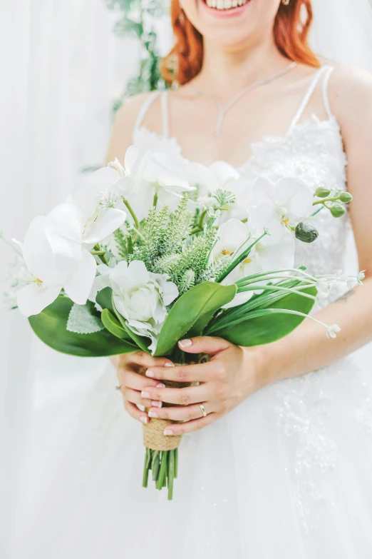 a smiling bride holding white flowers in her hands