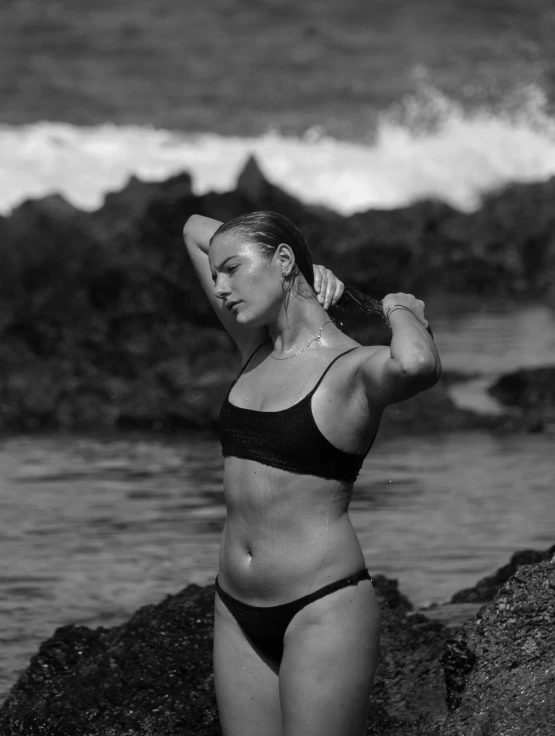 a woman in a bikini posing near the ocean