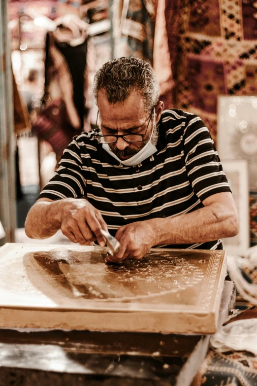 a man working on a piece of wood on a table